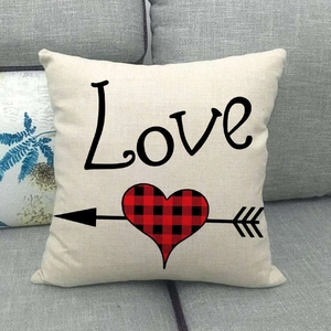 Détail de la housse de coussin en lin avec texte Love et cœur à carreaux sur canapé