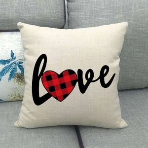 Détail de housse de coussin en lin avec cœur à carreaux et lettrage love sur un canapé