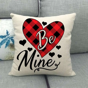 Détail de la housse de coussin en lin avec cœur à carreaux et texte Be Mine sur canapé