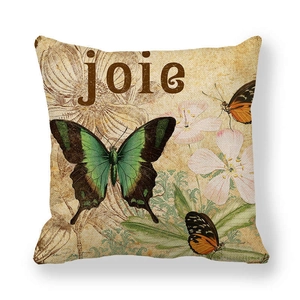 Détail de la housse de coussin en lin montrant des papillons et le texte joie