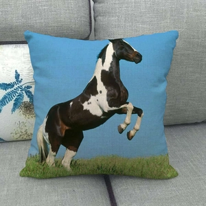 Detail of running horse pattern on textured linen cushion cover on a grey sofa