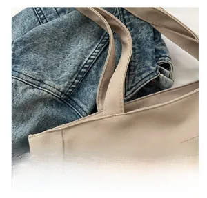 Detail of beige canvas tote bag showing reinforced handles and front zipper pocket