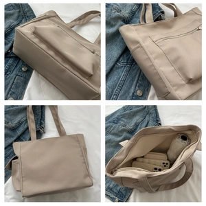 Detail view of large beige canvas tote bag with front zip pocket and spacious interior