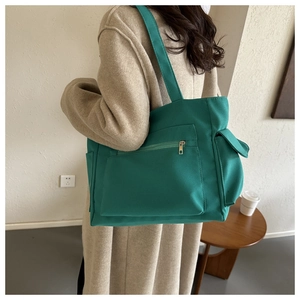 Detail of teal canvas tote bag featuring front zipper pocket and side flap pocket details