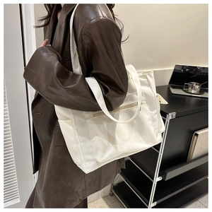 Detail of off-white large capacity tote bag with zipper pockets worn by a model