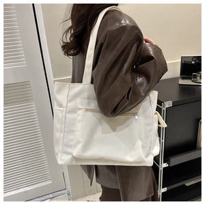 Side view of white canvas tote bag with front zipper pocket on a model with leather jacket