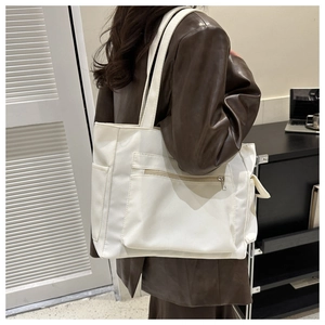 Detail view of large white tote bag with side pockets and zipper on female model