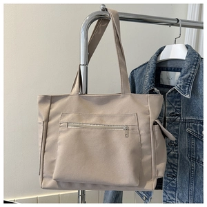 Detailed view of beige canvas tote bag with front zip pocket and side compartments