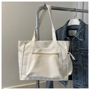 Detail view of white canvas tote bag with front zipper pocket and side functional pockets