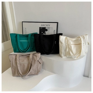 Detail view of canvas tote bags in four colors with front zipper pockets and side pockets