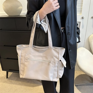 Minimalist beige large tote bag with multi-pocket design shown on shoulder