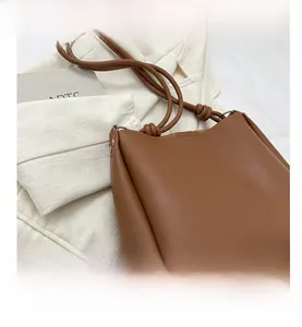 Close-up of caramel brown leather tote bag showing knot strap and silver ring detail