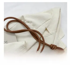 Detail of a brown leather tote bag showing the knotted handle design and silver metal rings