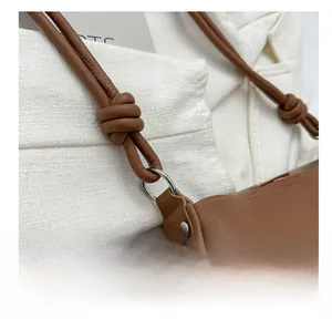 Detail of a brown leather bag showing knotted shoulder strap and silver metal hardware