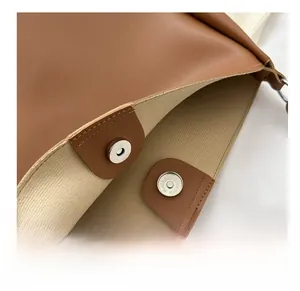Close-up of high-quality magnetic hardware buckle and fabric lining on brown leather tote