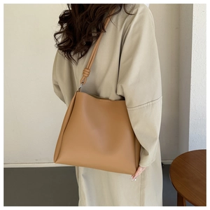 Detailed side view of caramel leather tote bag with knotted strap and silver hardware