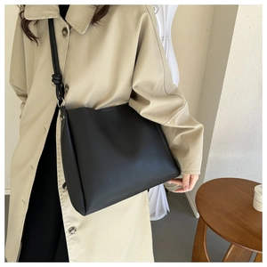 Detail shot of a black leather bucket bag featuring a unique knot design on the shoulder strap