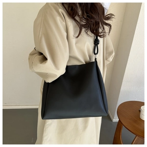 Detail of minimalist black matte tote bag featuring stylish knotted strap and metal ring