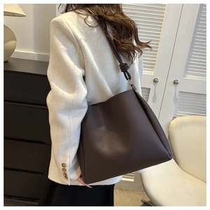 Detailed close-up of dark brown leather tote bag with stylish knot strap and matte finish