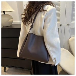 Detail shot of a dark brown leather tote bag featuring a minimalist side knot design