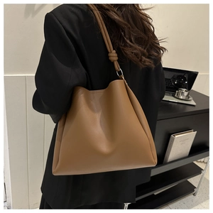 Brown leather tote bag featuring a minimalist knotted shoulder strap with metal ring detail