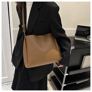 Close-up of minimalist brown leather tote bag with unique knot detail on the shoulder strap