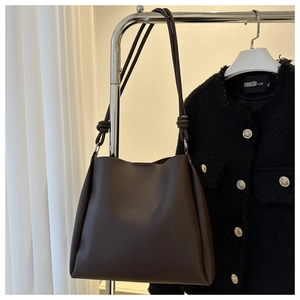 Close-up of dark brown leather tote bag with unique knot detail on the shoulder strap