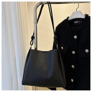 Close-up of a black minimalist tote bag with knot details on a metal hanger