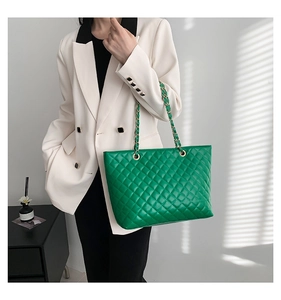 Chic quilted bright green tote bag with metallic chain strap worn by a model