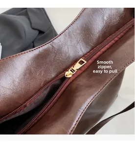 Détail de la fermeture éclair en métal doré lisse sur un sac en cuir marron foncé