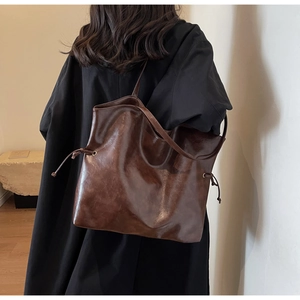 Detail of deep brown retro tote bag with adjustable drawstring on model side