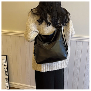 Détail du grand sac cabas en cuir noir brillant avec bandoulière réglable et design élégant