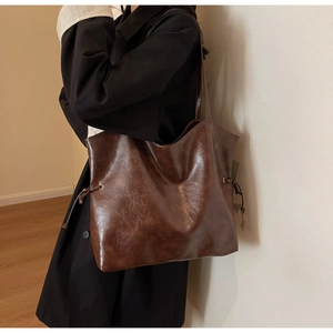 Close-up of deep brown tote bag featuring retro pleated faux leather and drawstring detail