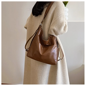 Détail de la sangle réglable et poche latérale sur grand sac cabas en cuir marron