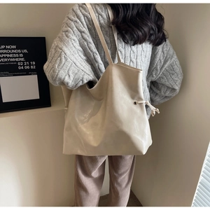 Détail d'un grand sac cabas crème en similicuir avec cordon de serrage sur modèle