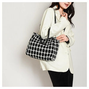 Detail of black and white plaid tweed tote bag with leather strap and metal chain