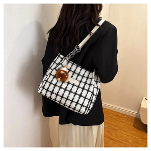Detail of checkered tweed tote bag with leather chain strap and plush ball charm