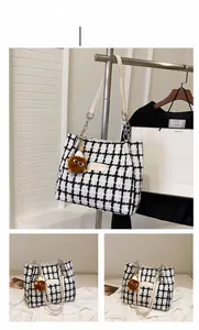 Detail of checkered woven tote bag with chain strap and brown plush bear charm