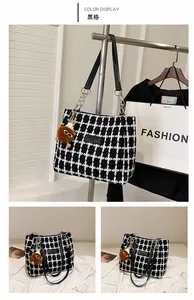 Detail of wool tote bag featuring black plaid pattern and plush charm with chain strap