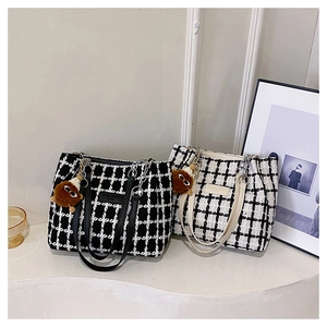 Detail of checkered tweed tote bags with leather handles and plush charm accessory