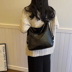 Sac hobo minimaliste en cuir noir avec large bandoulière et poche frontale pratique