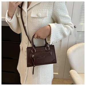Detail of dark brown vintage faux leather crossbody bag with tassel zippers and dual handles