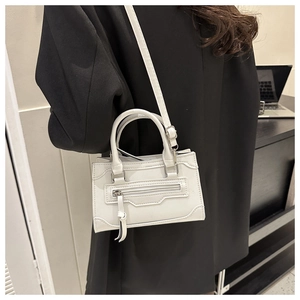 British style white leather crossbody bag with metal zipper and tassel detail shown on model