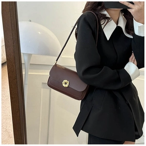 Vue détaillée du sac à bandoulière en cuir marron avec un fermoir tournant doré élégant