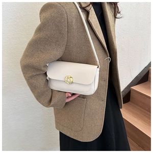 Détail d'un sac à bandoulière blanc avec une élégante boucle en métal doré en forme de nœud