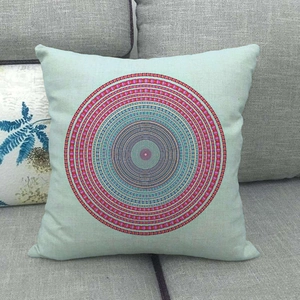Close-up of square linen pillowcase with colorful mandala geometric print on a grey sofa