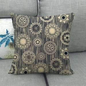 Détail de la housse de coussin en lin à motif mandala et rayures sur un canapé gris