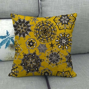 Détail de la housse de coussin jaune en lin avec motifs mandalas sur un canapé gris