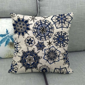 Détail de la housse de coussin en lin à motif mandala géométrique sur un canapé gris