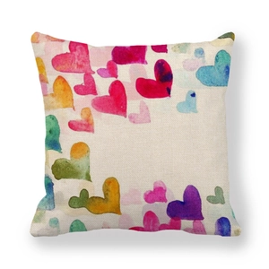 Close-up of linen cushion cover with colorful watercolor heart patterns on white background